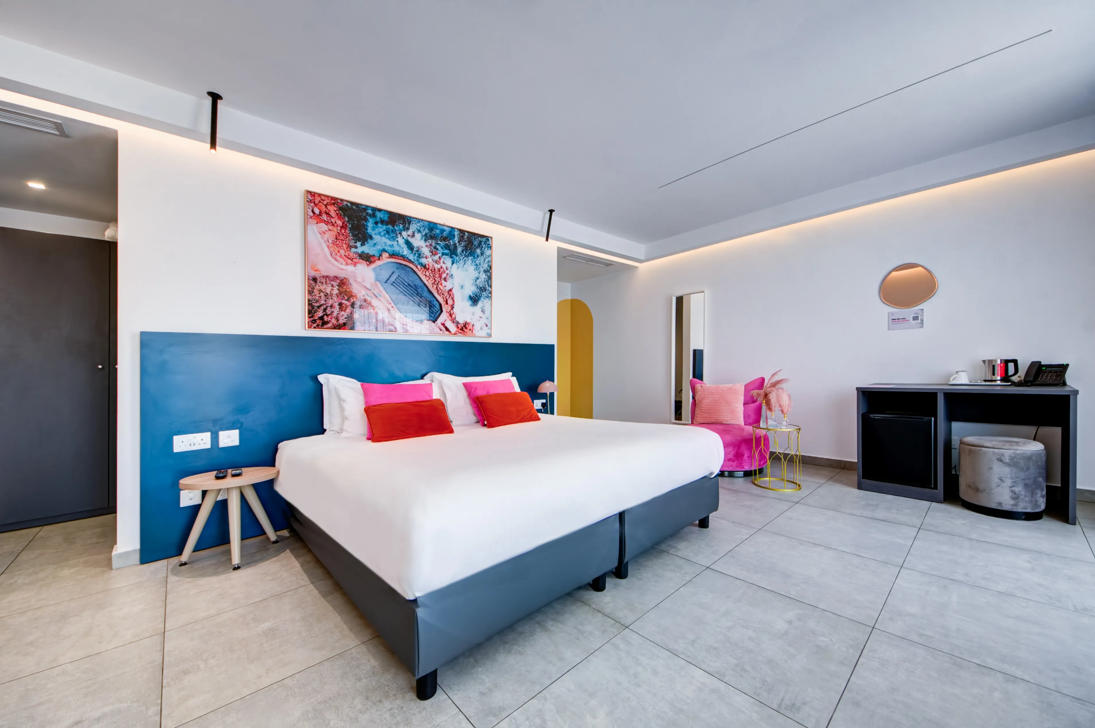 Accessible Room with spacious layout, beach art above bed and pink accent chair