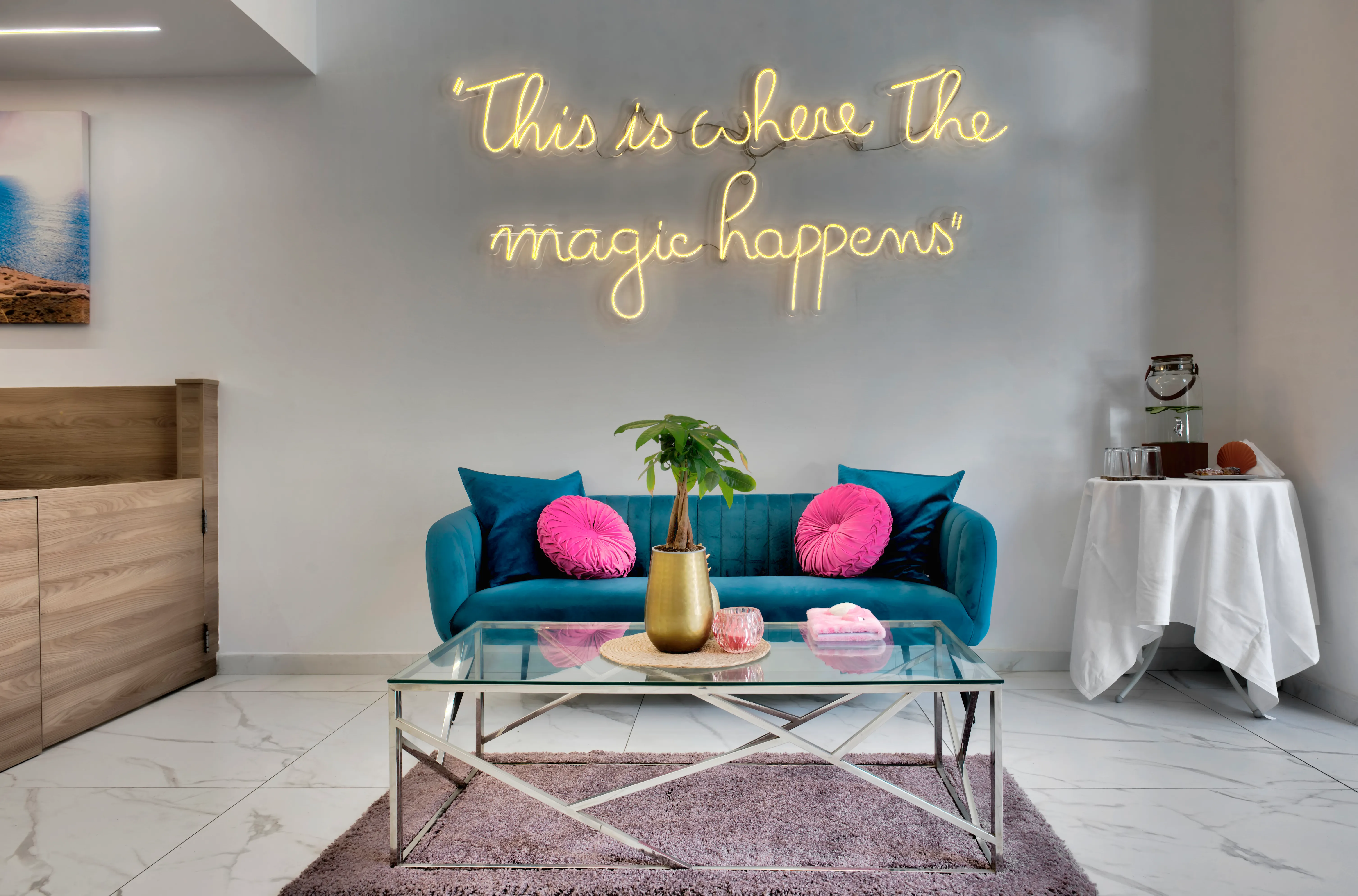 Lounge with neon sign reading This is where the magic happens