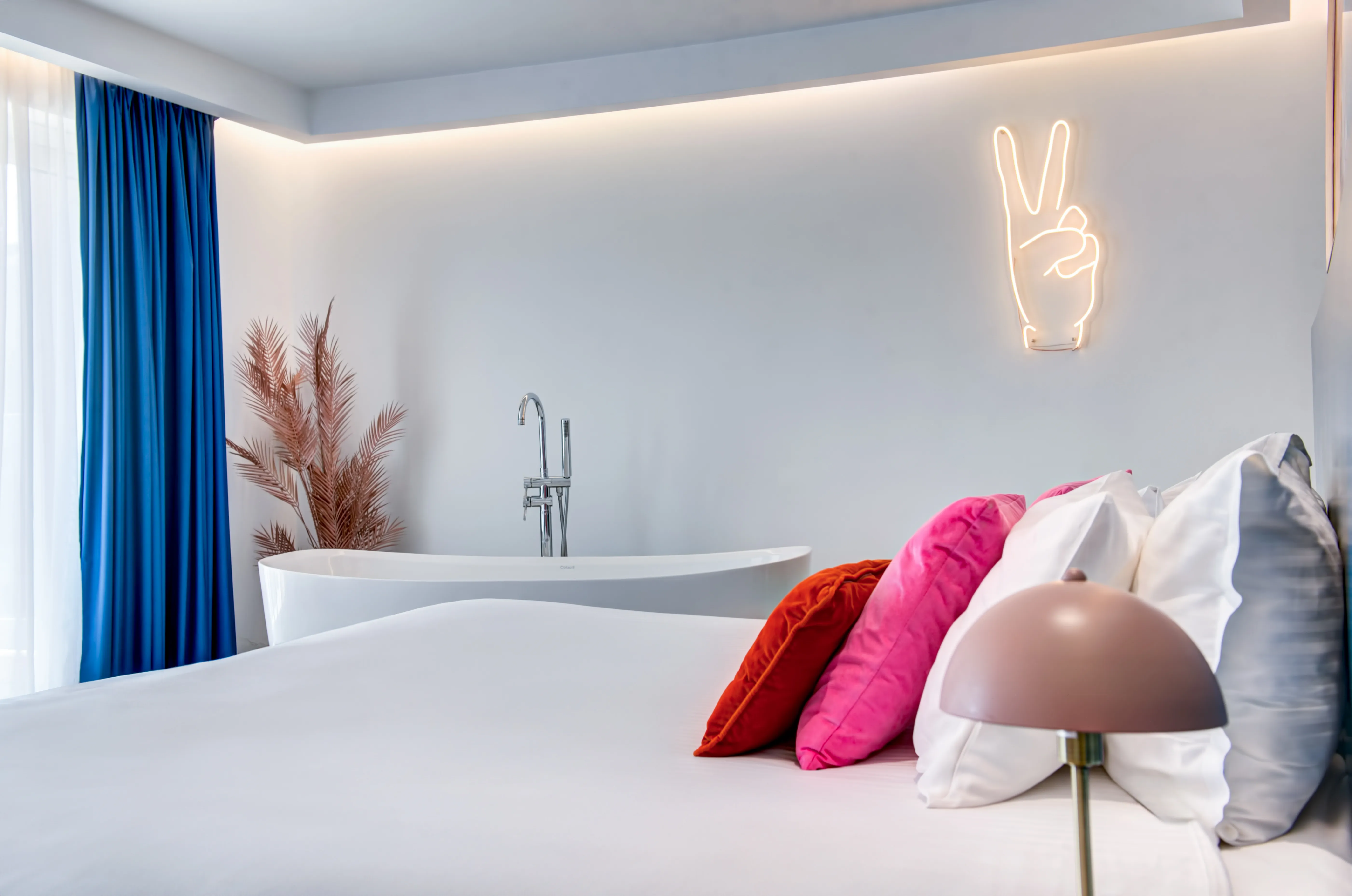 Peace sign neon light above bed with colorful pillows